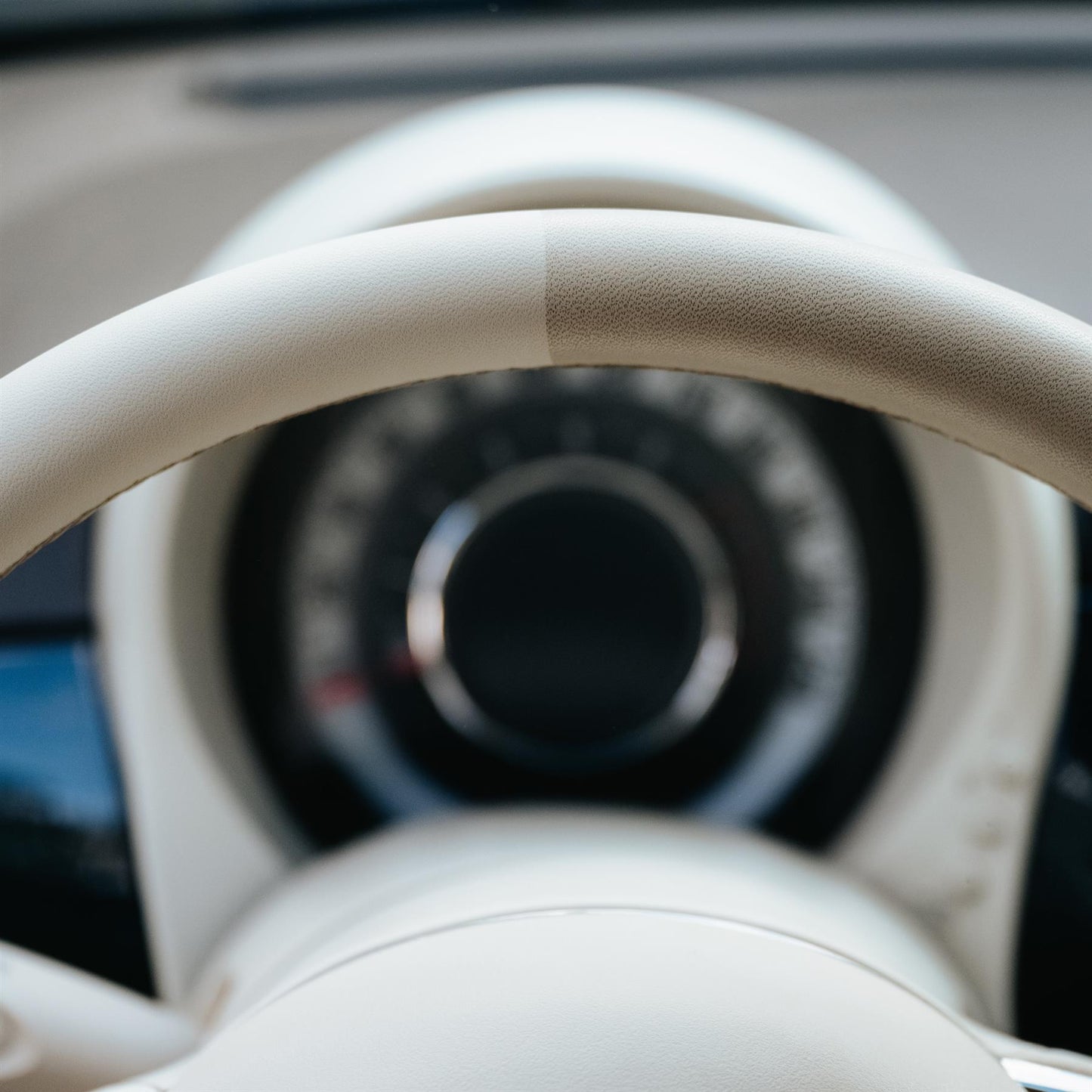 Car care image showing a cream steering wheel, half of it cleaned. Car interior detailing product efficacy shot.