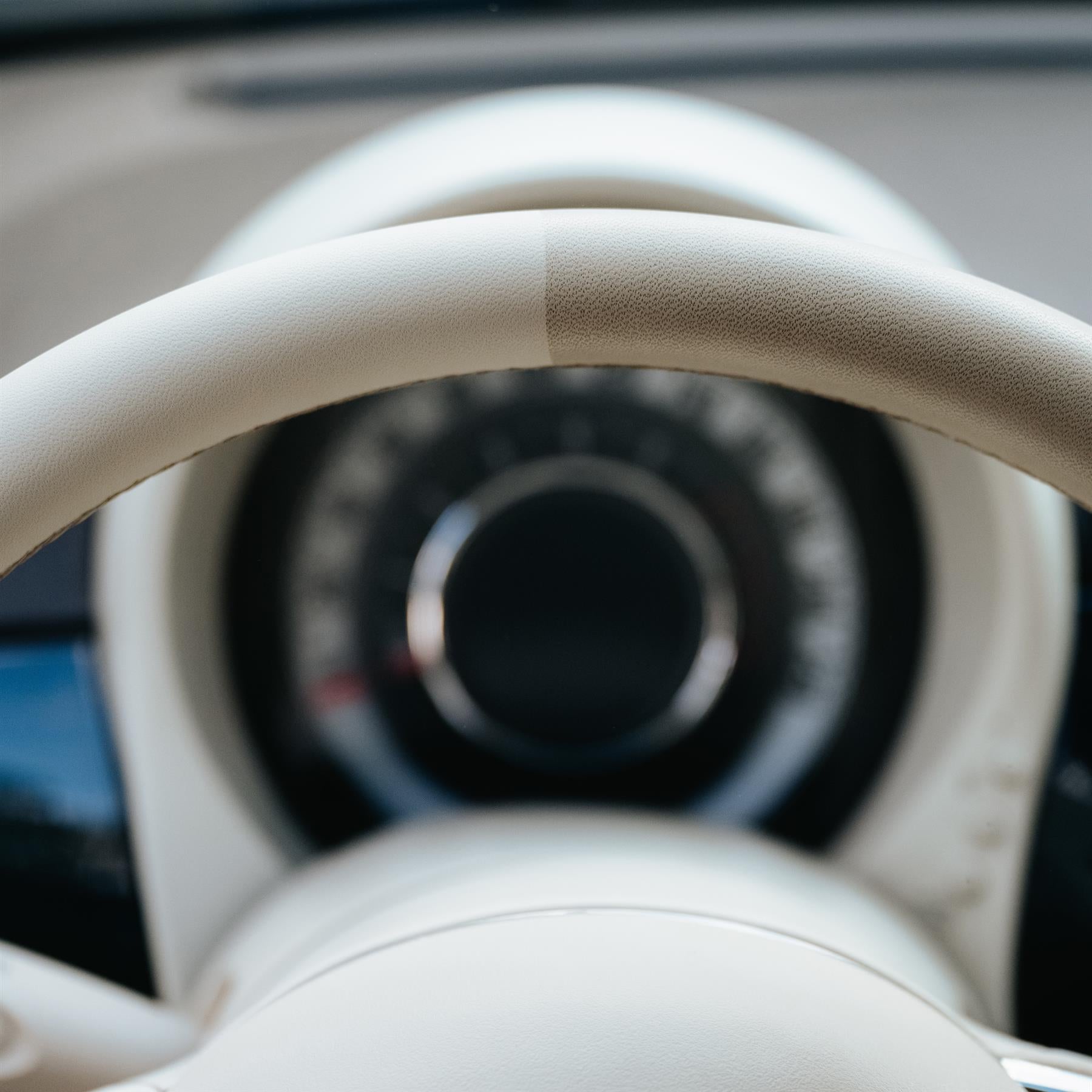 Car care image showing a cream steering wheel, half of it cleaned. Car interior detailing product efficacy shot.