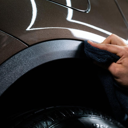 Applying detailing product with cloth to a vehicle's trim and tyre. The Turtle Wax logo isn't visible.