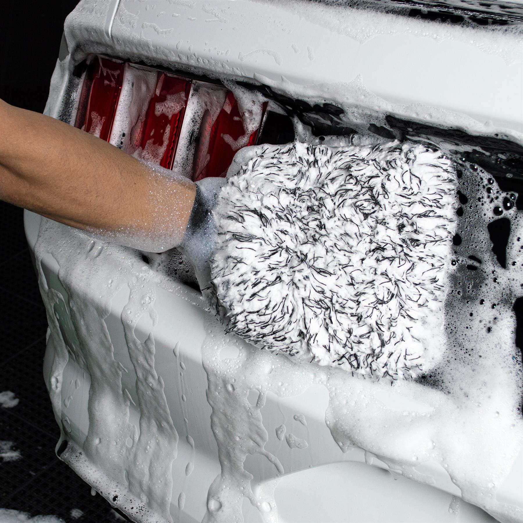 Microfibre wash mitt cleaning a car. Soapy, close-up view of auto detailing.
