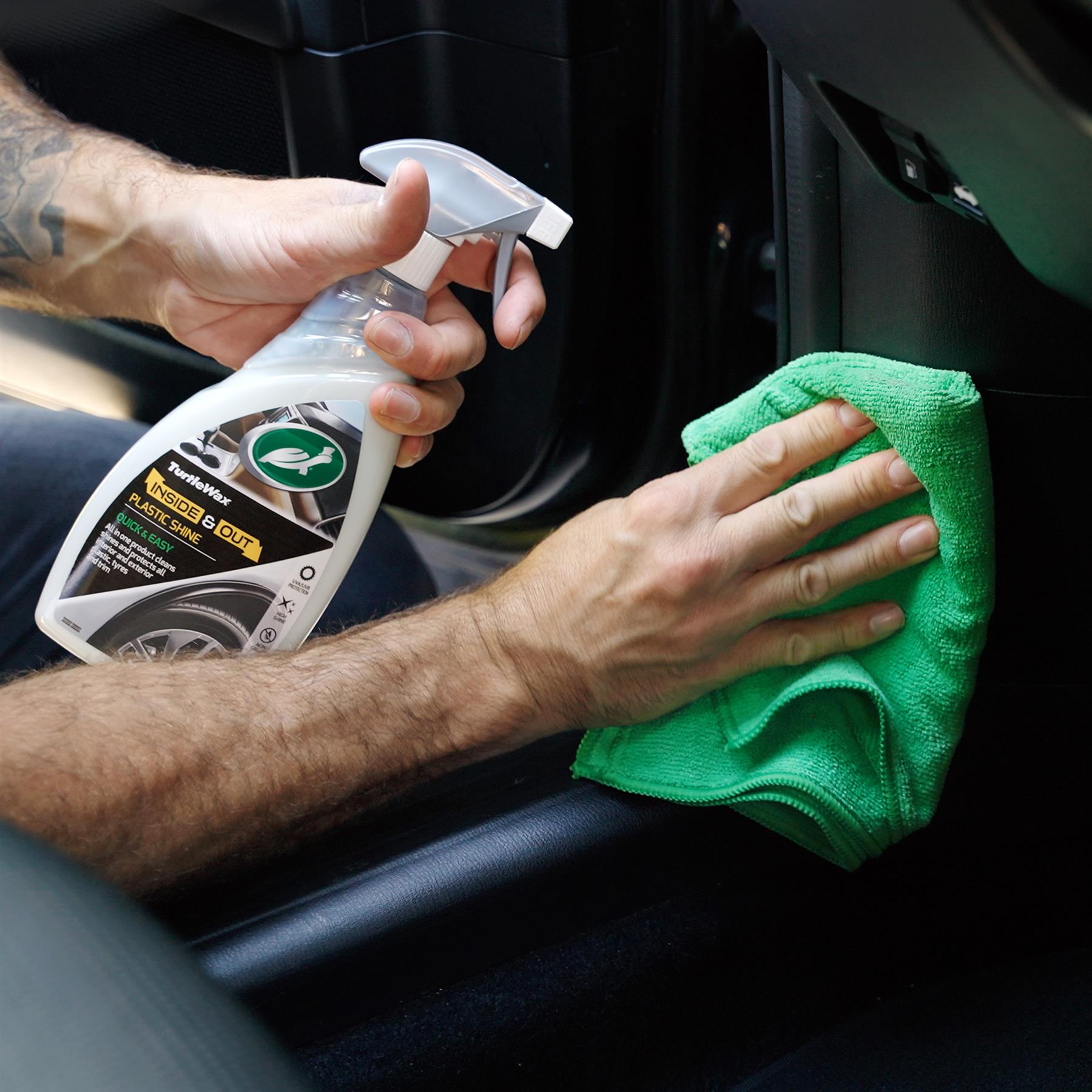 Turtle Wax "Inside & Out" plastic cleaner being used inside a car. The cleaner is sprayed, then wiped with a green microfibre cloth.