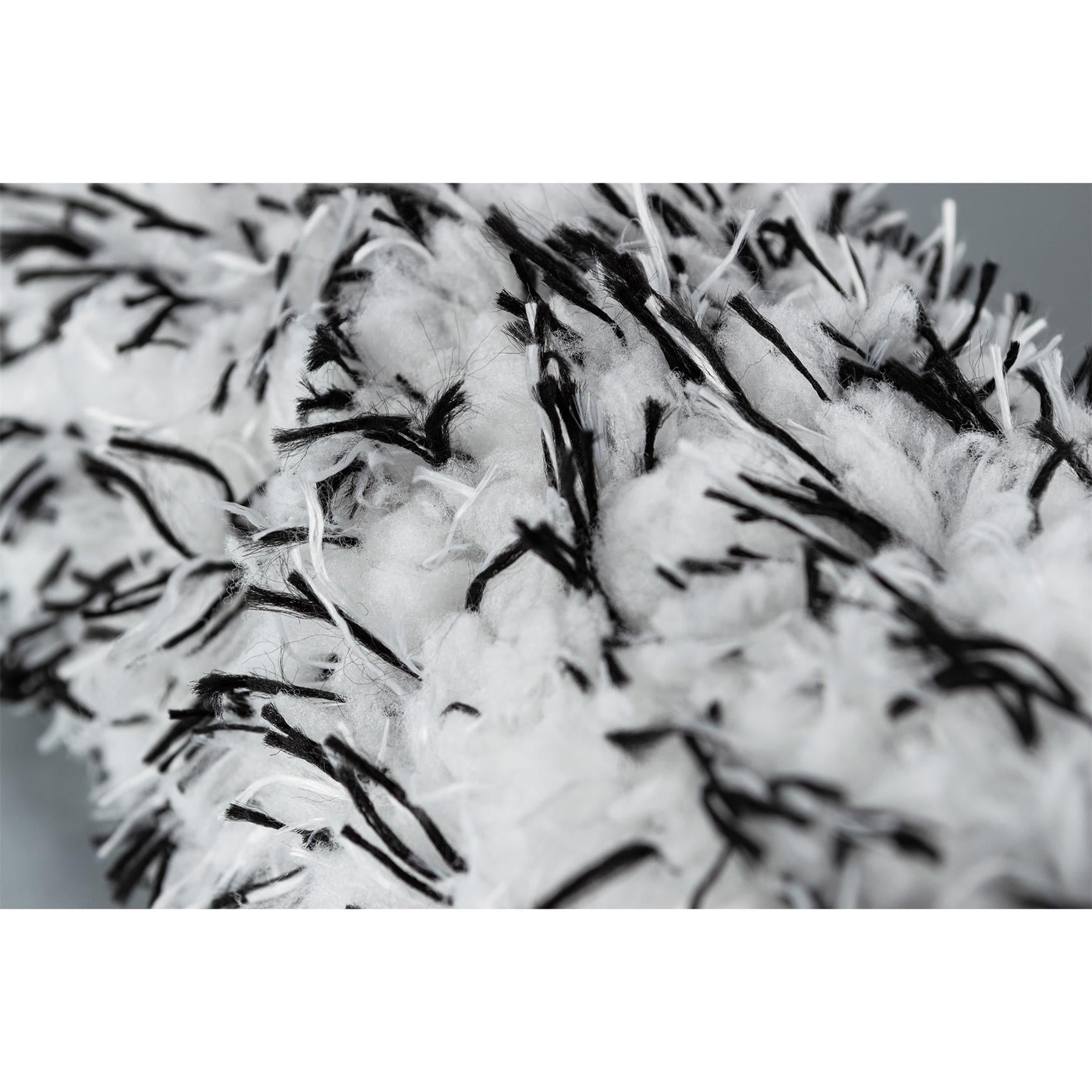 Close-up on a fluffy, white wheel cleaning brush with black filaments. Auto detailing equipment.