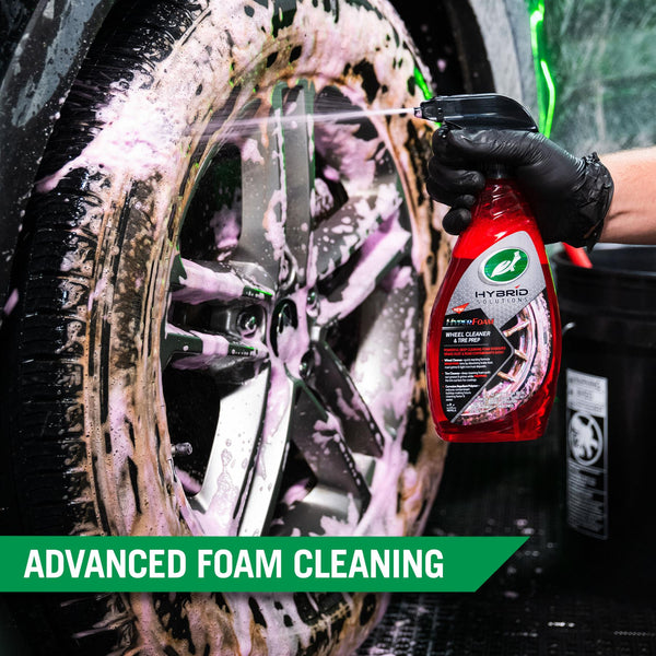 Bottle of detailing spray placed on a polished car fender, highlighting reflections and sleek car body lines.