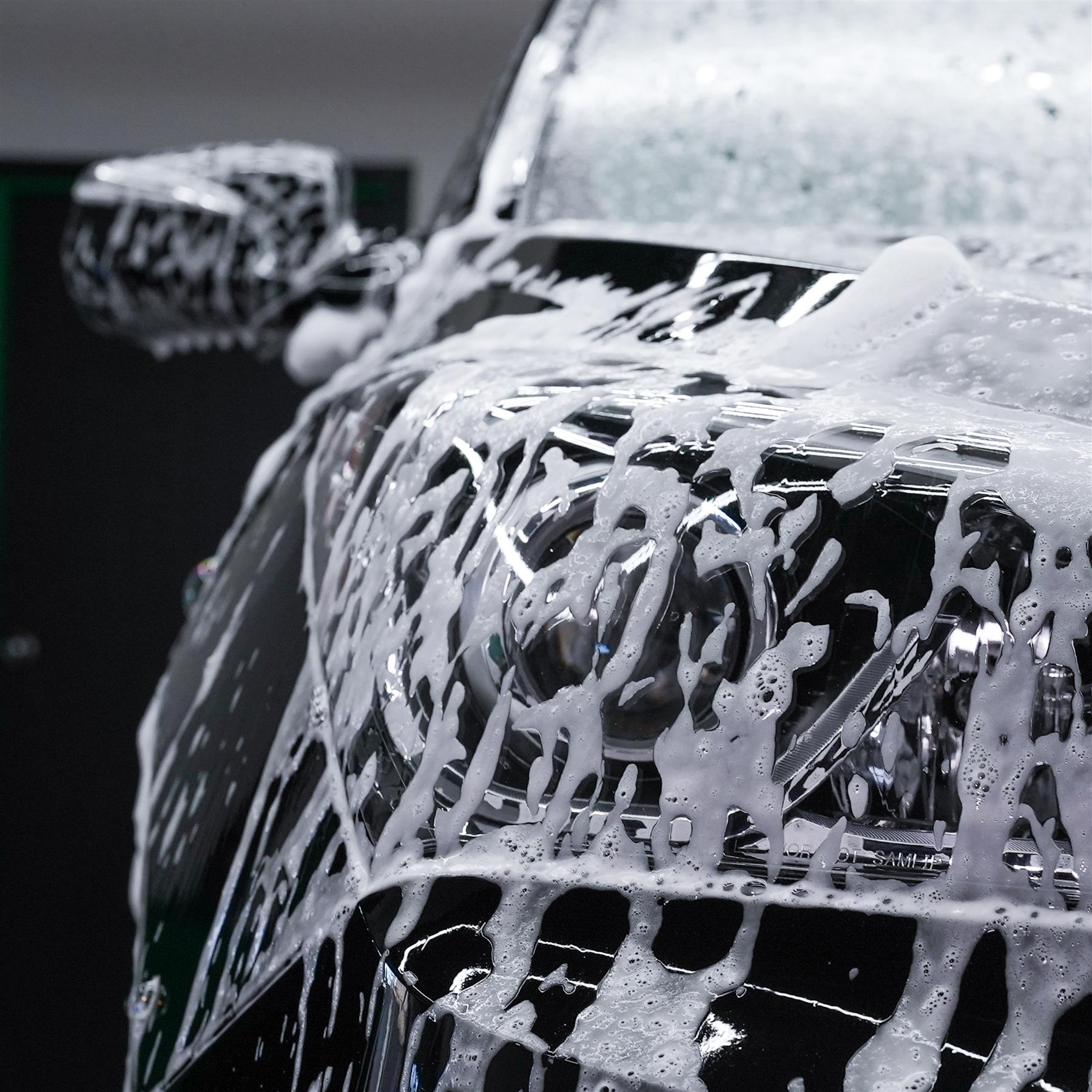 Foam-covered car headlight. Cleansing and detailing for a gleaming vehicle. Car care.