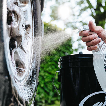 Cleaning alloy wheels. A person spraying solution onto the dirty metal hub. Turtle Wax bucket nearby.