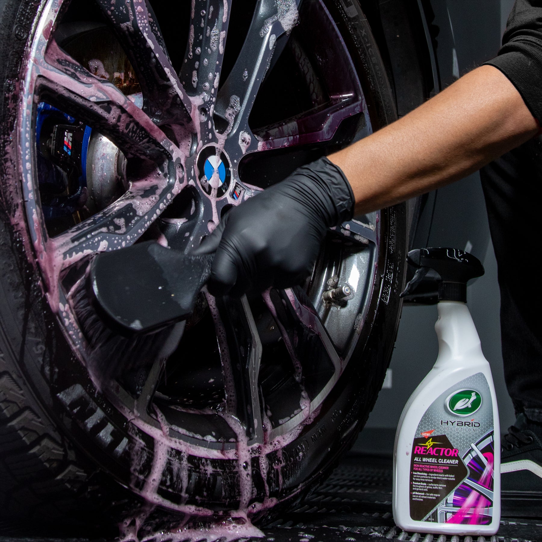 Detailing a BMW wheel with Turtle Wax Hybrid Solutions Reactor. Pink suds cover the alloy as grime is brushed away.
