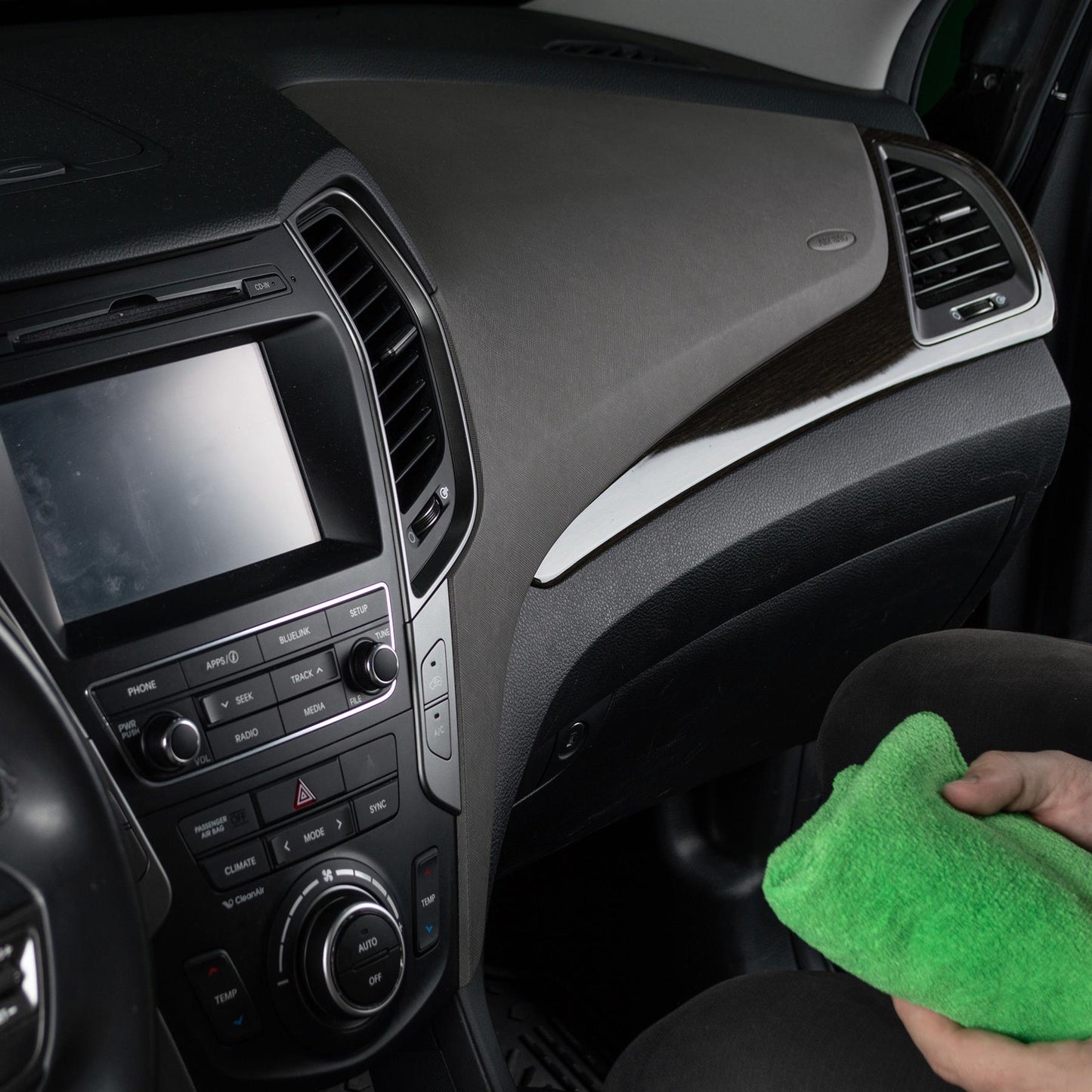 Car detailing: Interior dashboard being cleaned with a green microfibre cloth. Perfect for automotive care.
