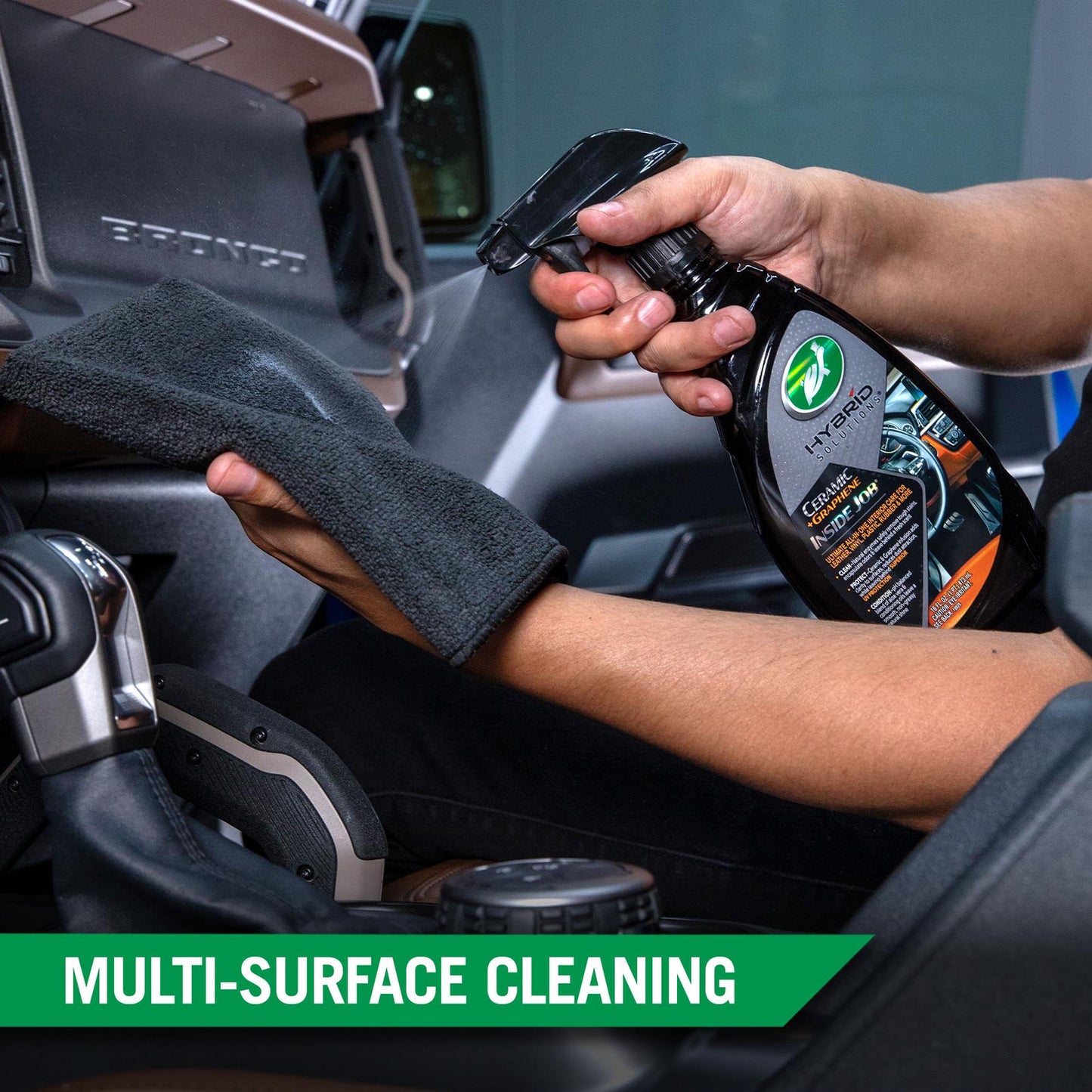 Auto detailer spraying Turtle Wax interior cleaner onto dashboard of a Bronco. Microfibre cloth in hand ready to wipe.
