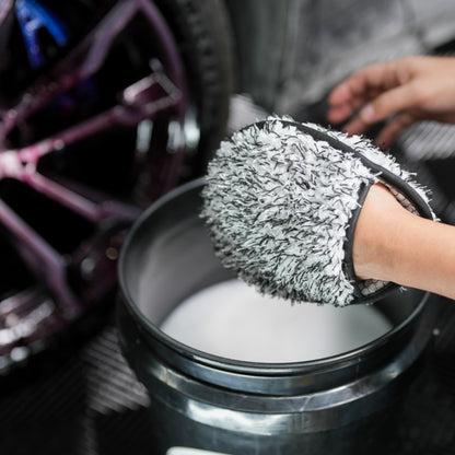 Car detailing: A microfibre wash mitt soaks in soapy water, ready to clean alloy wheels. Car care maintenance for a gleaming finish.
