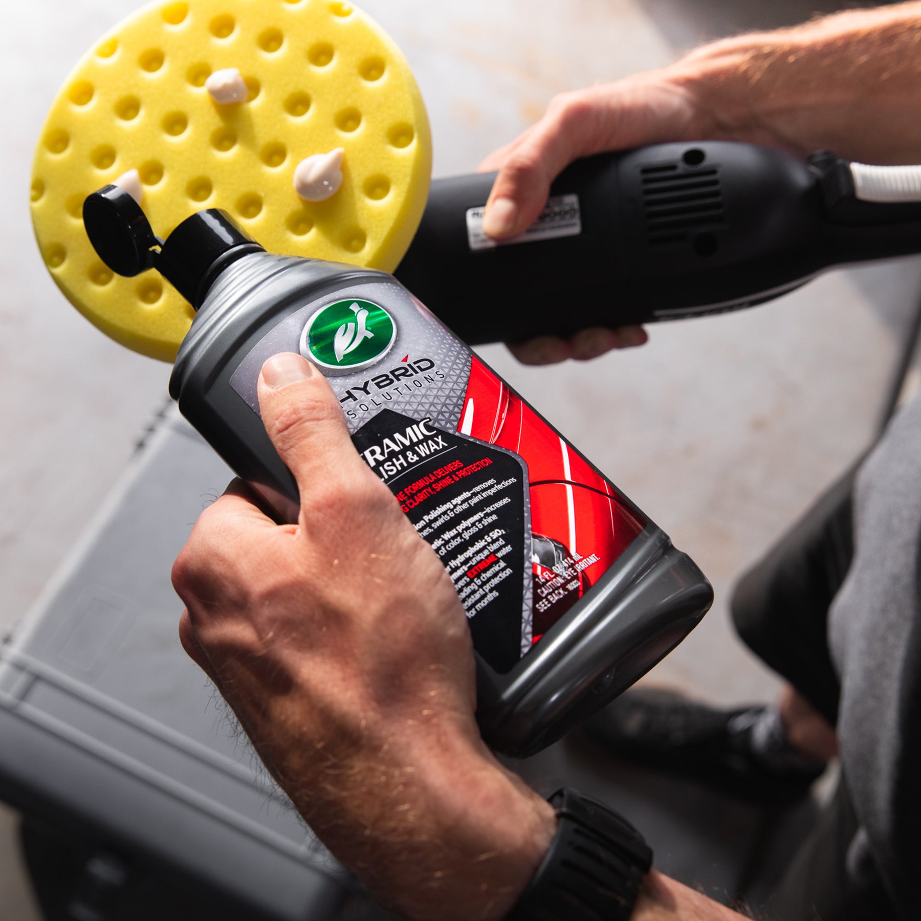Man applying Turtle Wax Hybrid Solutions ceramic polish to polishing pad before using a machine polisher. Car detailing.