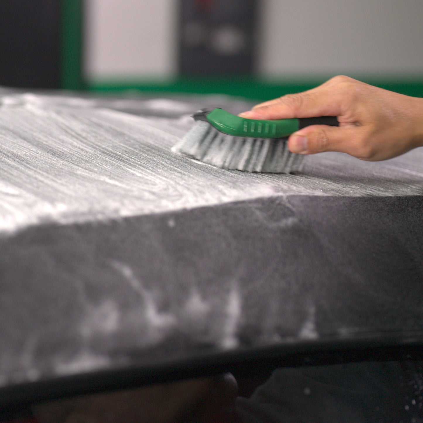 Hand brushing fabric with suds. Automotive detailing using Turtle Wax Hybrid Solutions for stain removal and deep clean.
