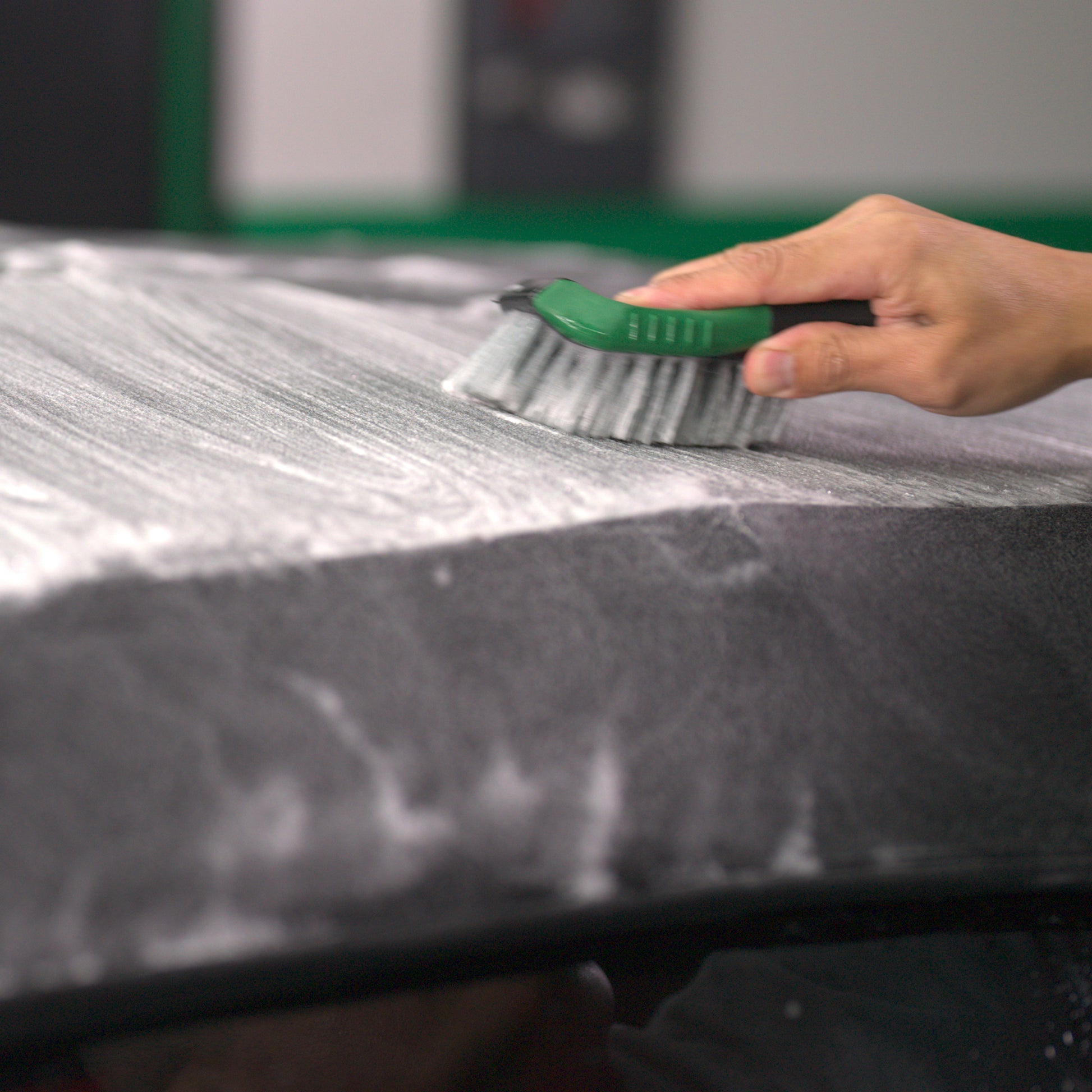 Hand brushing fabric with suds. Automotive detailing using Turtle Wax Hybrid Solutions for stain removal and deep clean.
