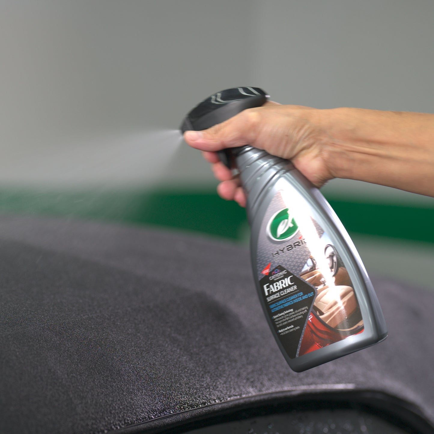 Turtle Wax Hybrid Solutions fabric cleaner being sprayed. Ideal for vehicle upholstery and interior cleaning projects.