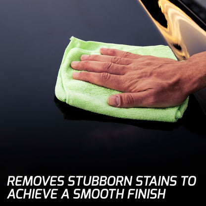 Polishing a vehicle's dark paintwork. A hand holds a green cloth on a car body panel for a clean, glossy shine.