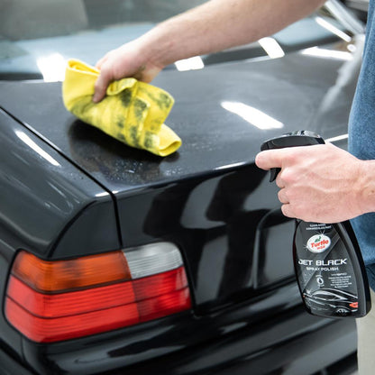 Polishing a black car boot with Turtle Wax Jet Black spray. A yellow microfibre cloth is being used to buff the surface. Car detailing.