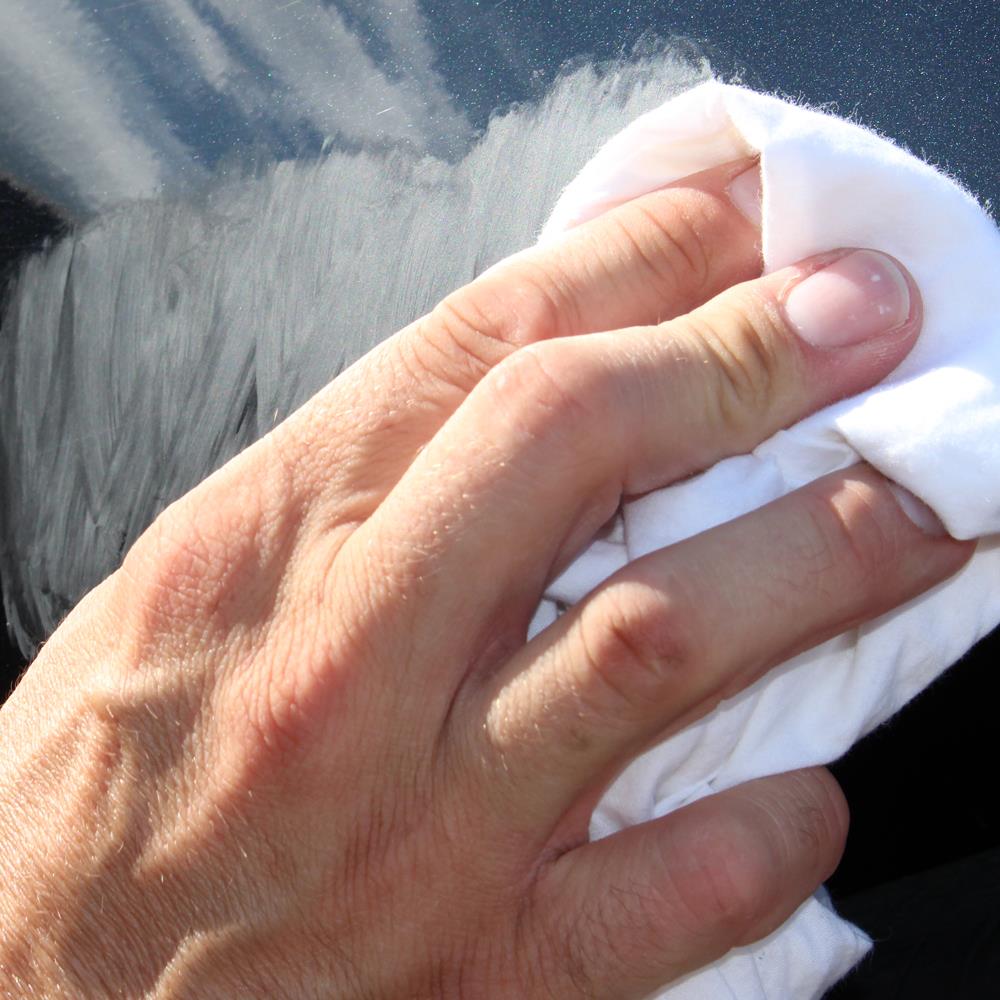 Hand buffing car paintwork. Car detailing concept for scratch removal, using a white cloth. 
