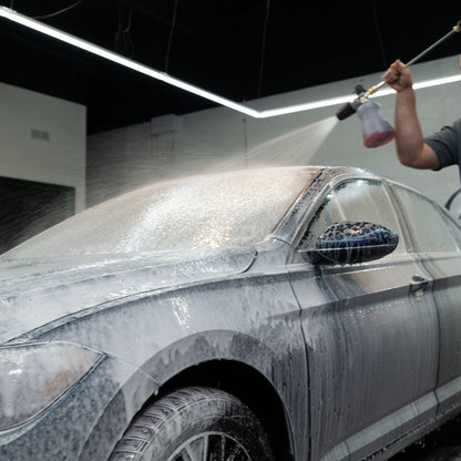 Car detailing: Sedan gets snow foam treatment from a pressure washer for deep car cleaning and valeting.