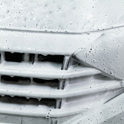 Car grille smothered in thick snow foam. Car detailing and valeting concept.