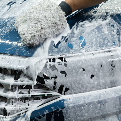 A car is being washed with a mitt and a snow foam formula leaving a streak-free finish.
