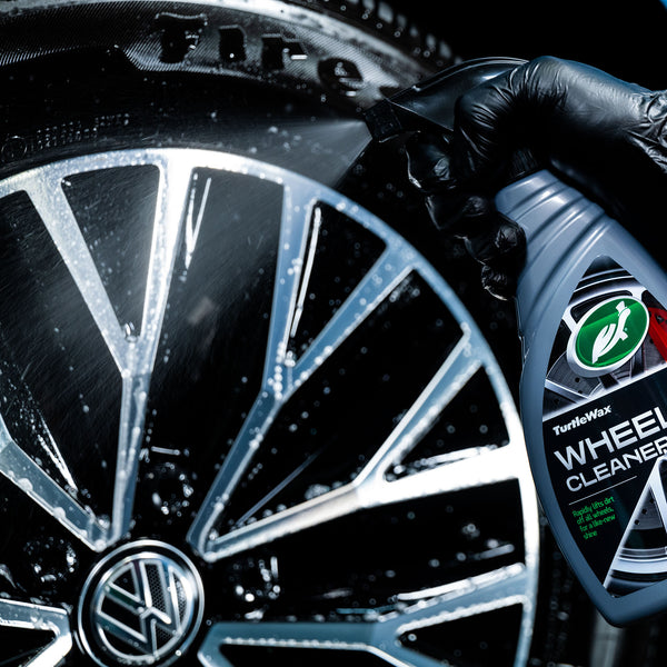 Hand holding product beside a car wheel demonstrating use positioning.