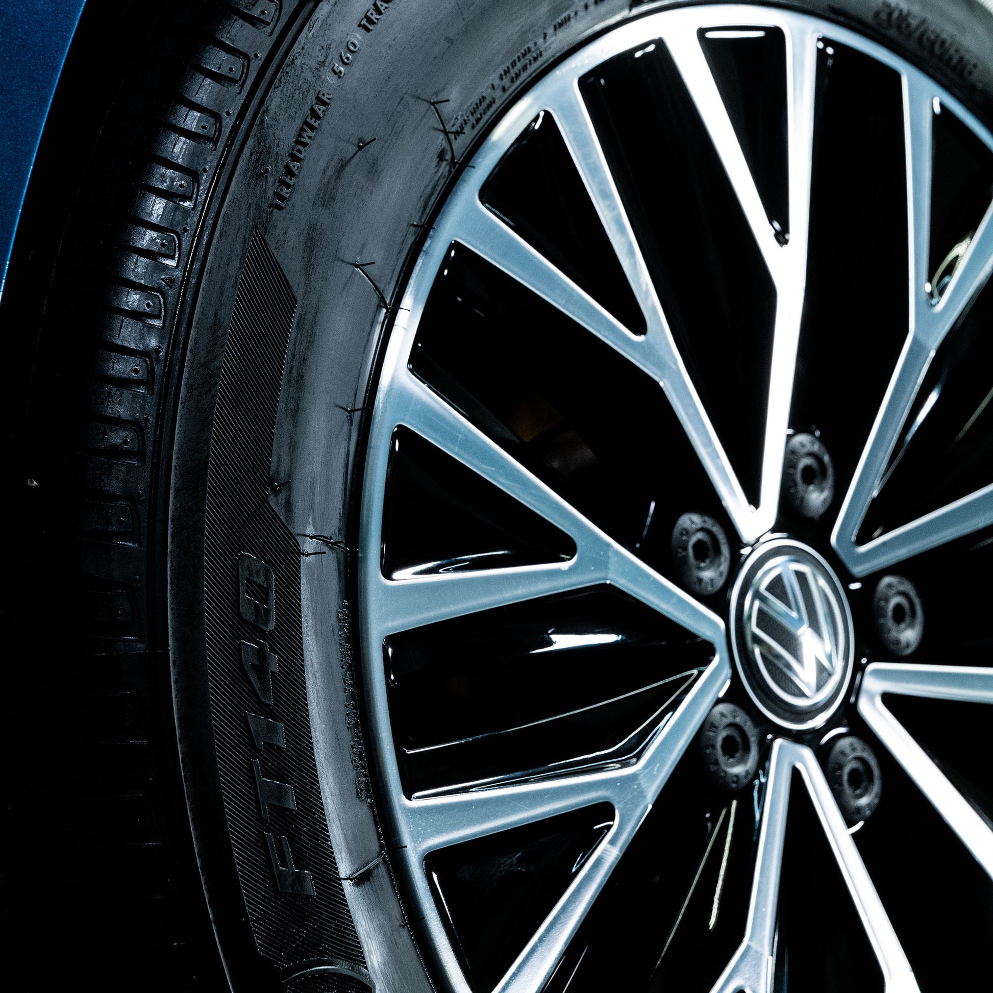 Shiny black tyre with detailed alloy wheel and Volkswagen logo. Automotive care and tyre protection.