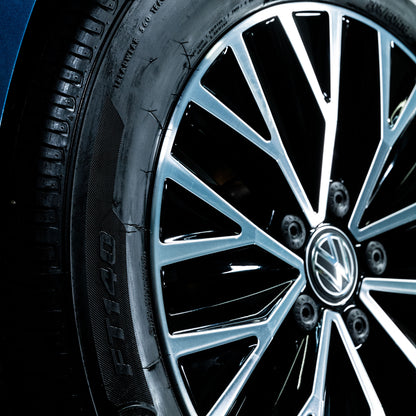 Shiny black tyre with detailed alloy wheel and Volkswagen logo. Automotive care and tyre protection.