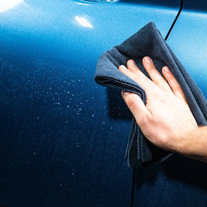 Car valeting: Hand polishing a blue car panel with a microfibre cloth. Detail shows before and after.
