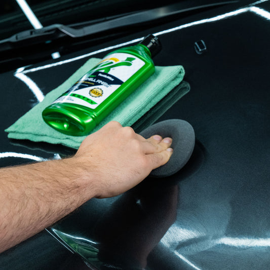 Shiny car finish with Turtle Wax bottle and applicator. Man's hand buffing vehicle paintwork.