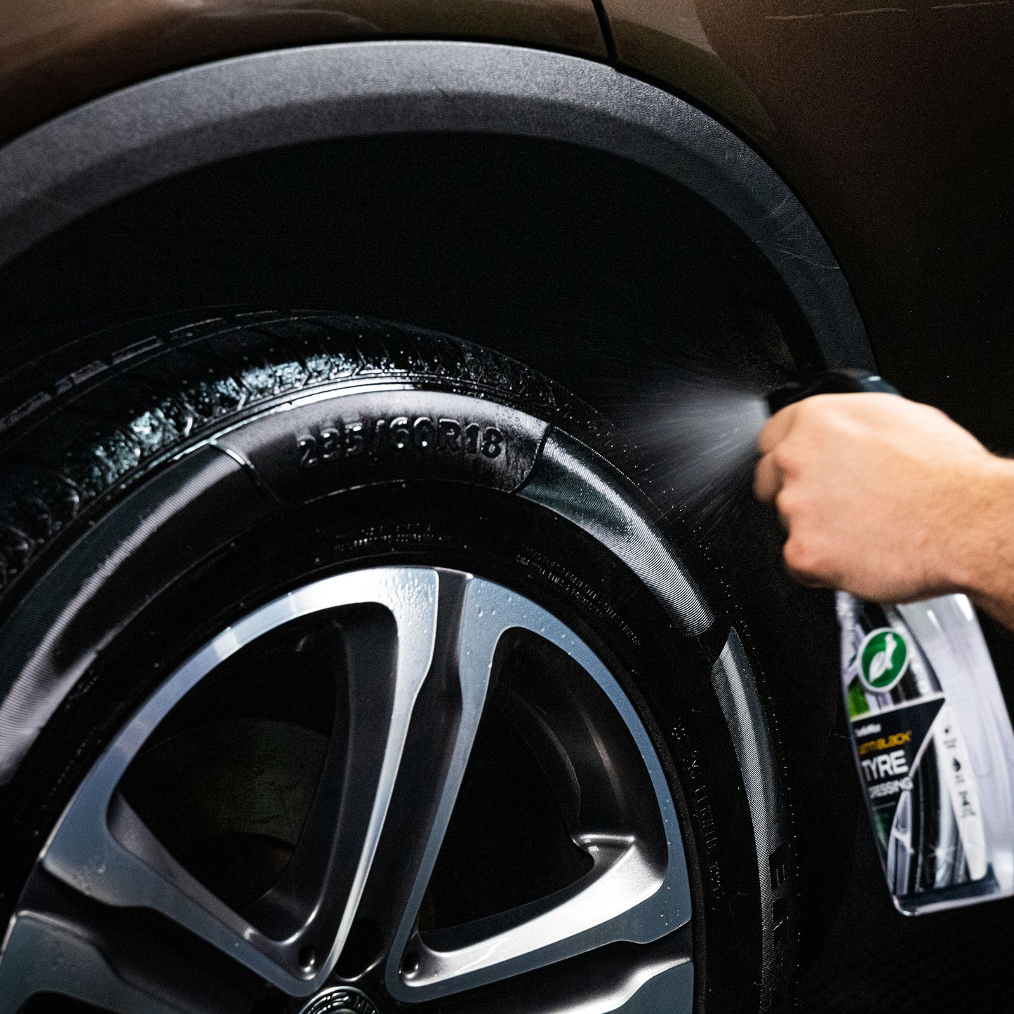 Turtle Wax tyre dressing being sprayed onto a car tyre to enhance its finish.