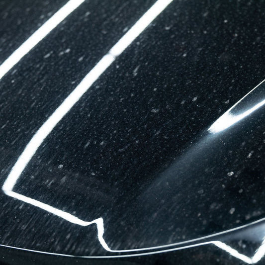 Dark, dirty car bonnet before cleaning. Bright lines indicate potential for a deep clean, or wax and shine with Turtle Wax.
