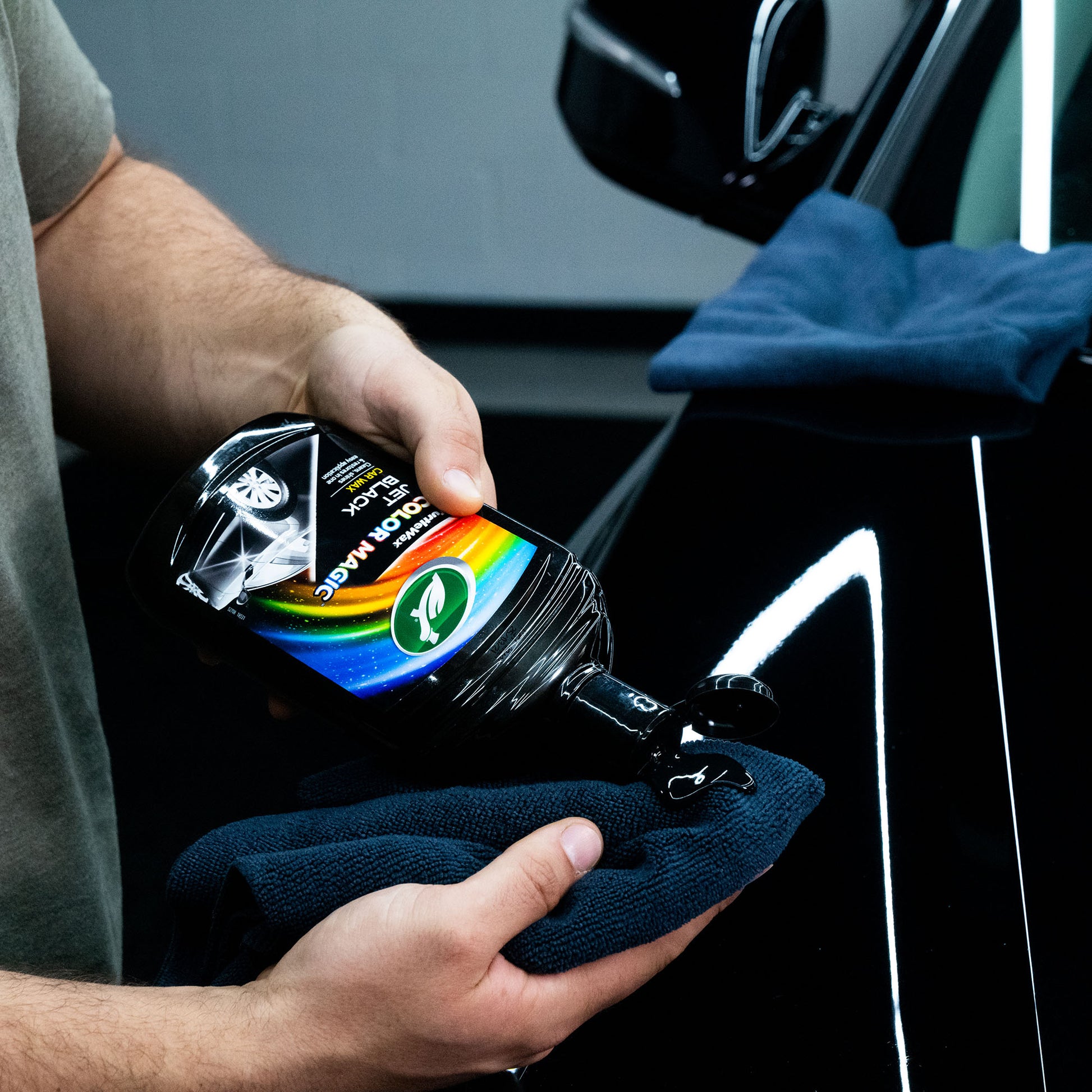 Person applies Turtle Wax Color Magic Jet Black Car Wax, 500ml, to a microfibre cloth for use on a black vehicle.
