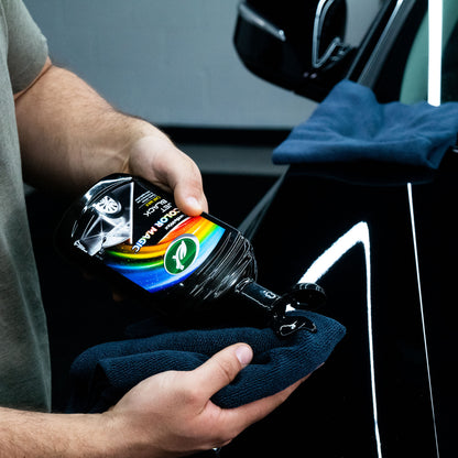 Person applies Turtle Wax Color Magic Jet Black Car Wax, 500ml, to a microfibre cloth for use on a black vehicle.