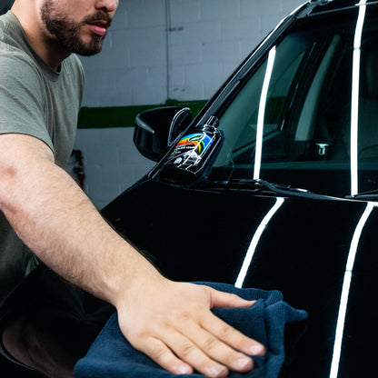 Polishing a black car. Man applies Turtle Wax Colour Magic black car polish with cloth for a glossy finish.