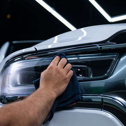 Car detailer using a cloth for headlight restoration on vehicle.