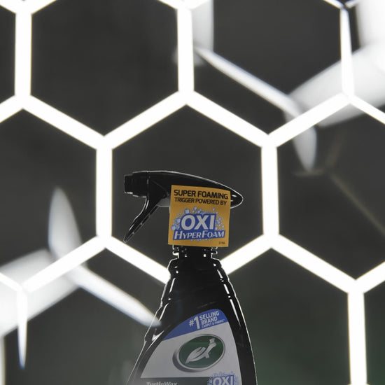 Side profile image of the Spot Clean bottle being held by a gloved hand for easy application on interior fabrics.