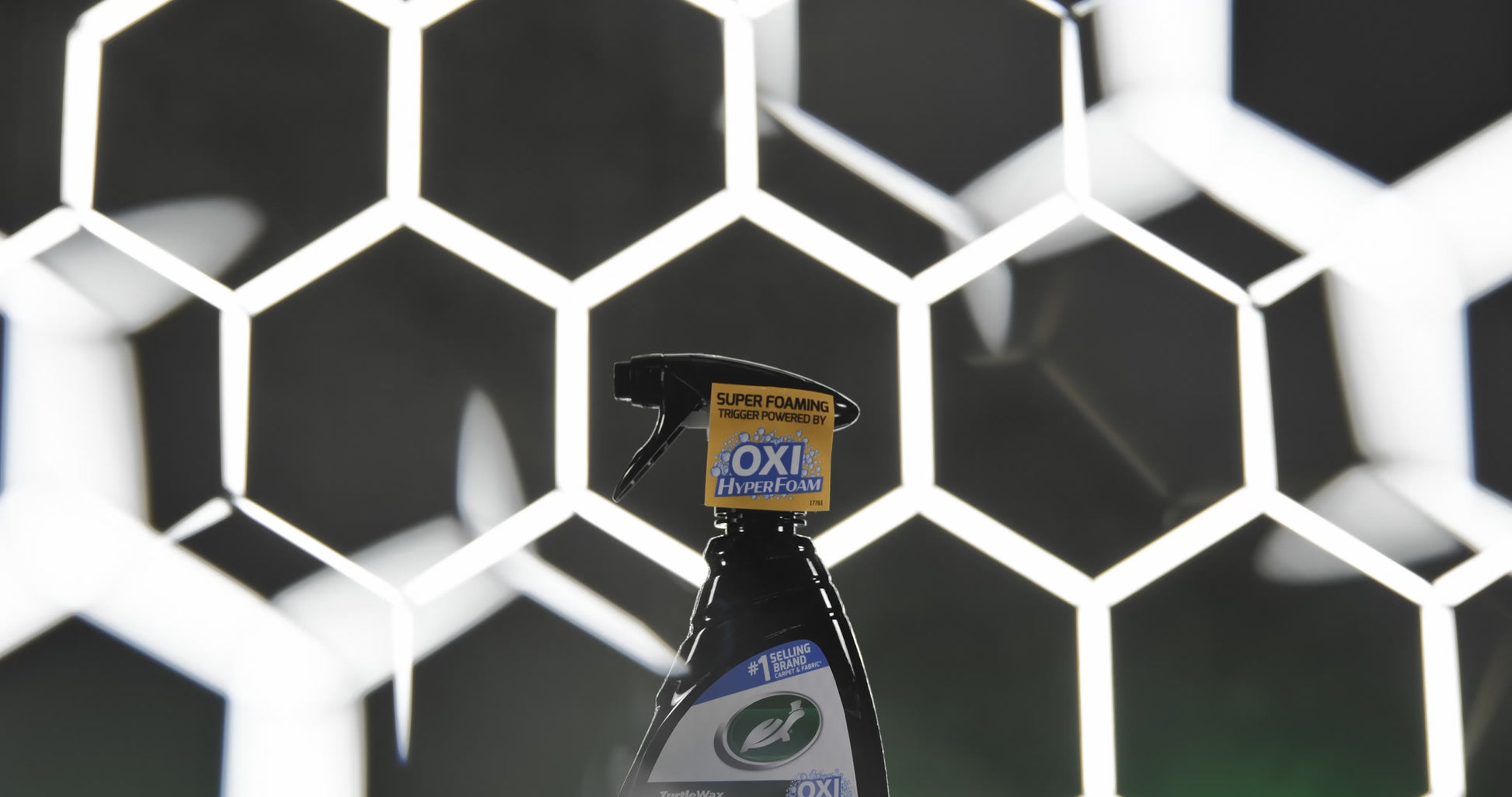 Side profile image of the Spot Clean bottle being held by a gloved hand for easy application on interior fabrics.