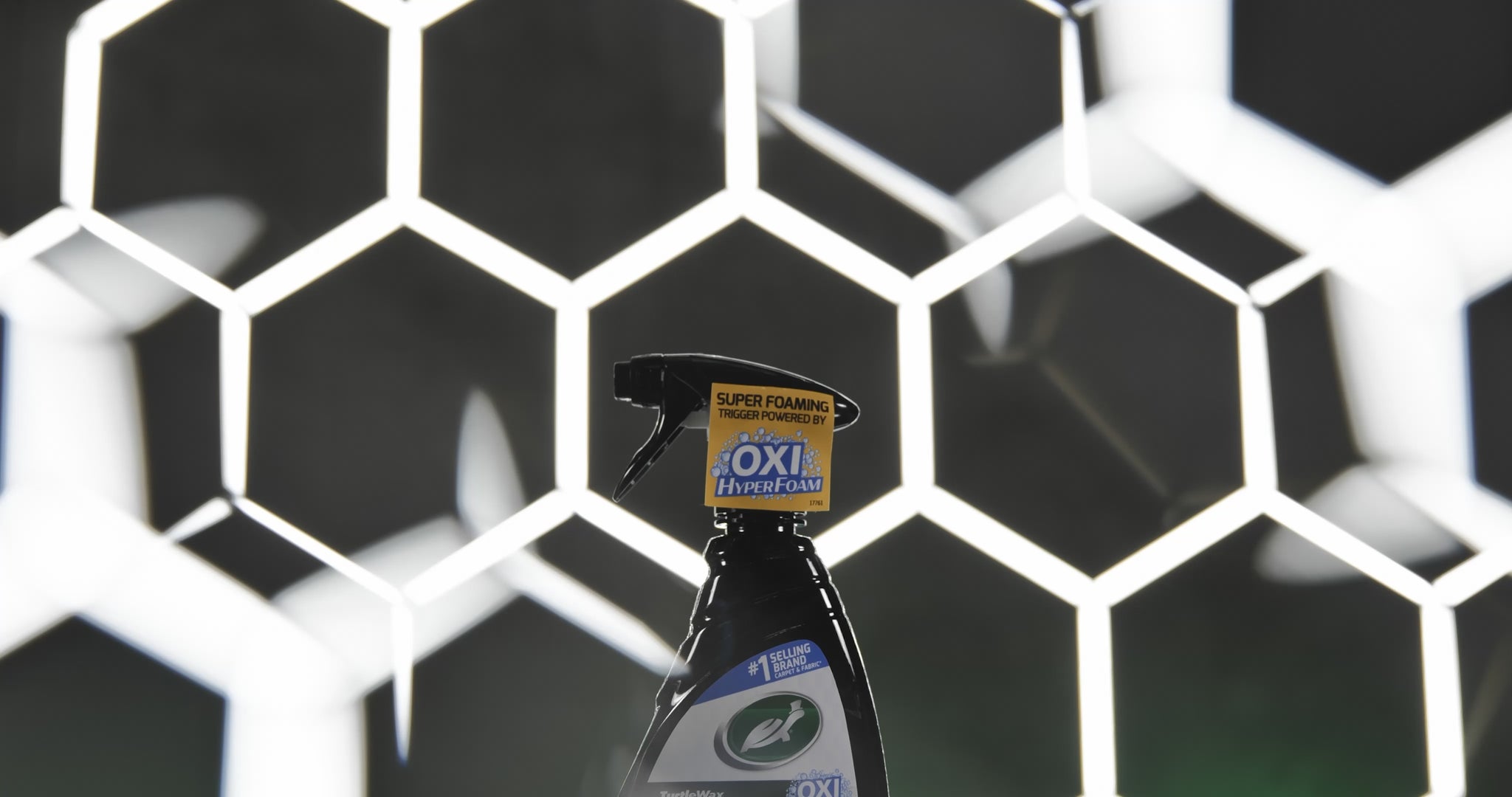 Side profile image of the Spot Clean bottle being held by a gloved hand for easy application on interior fabrics.